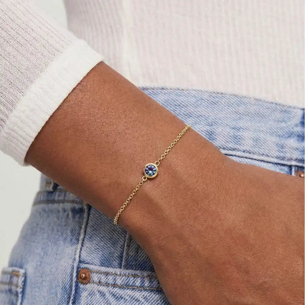 Model wearing bezel-set alexandrite bracelet. variant--14K-yellow-gold variant--Alexandrite