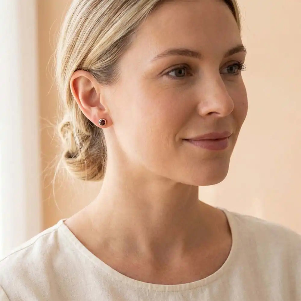 Garnet birthstone stud earrings on model, deep red studs at ear