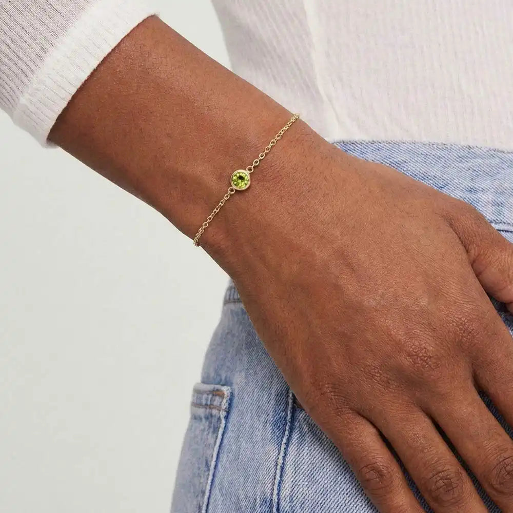 Model wearing bezel-set peridot bracelet. variant--14K-yellow-gold variant--Peridot