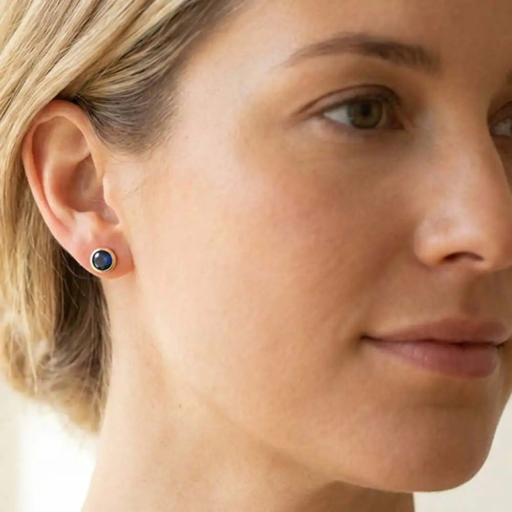 Sapphire birthstone stud earrings on model, deep blue studs at ear variant--14K yellow gold