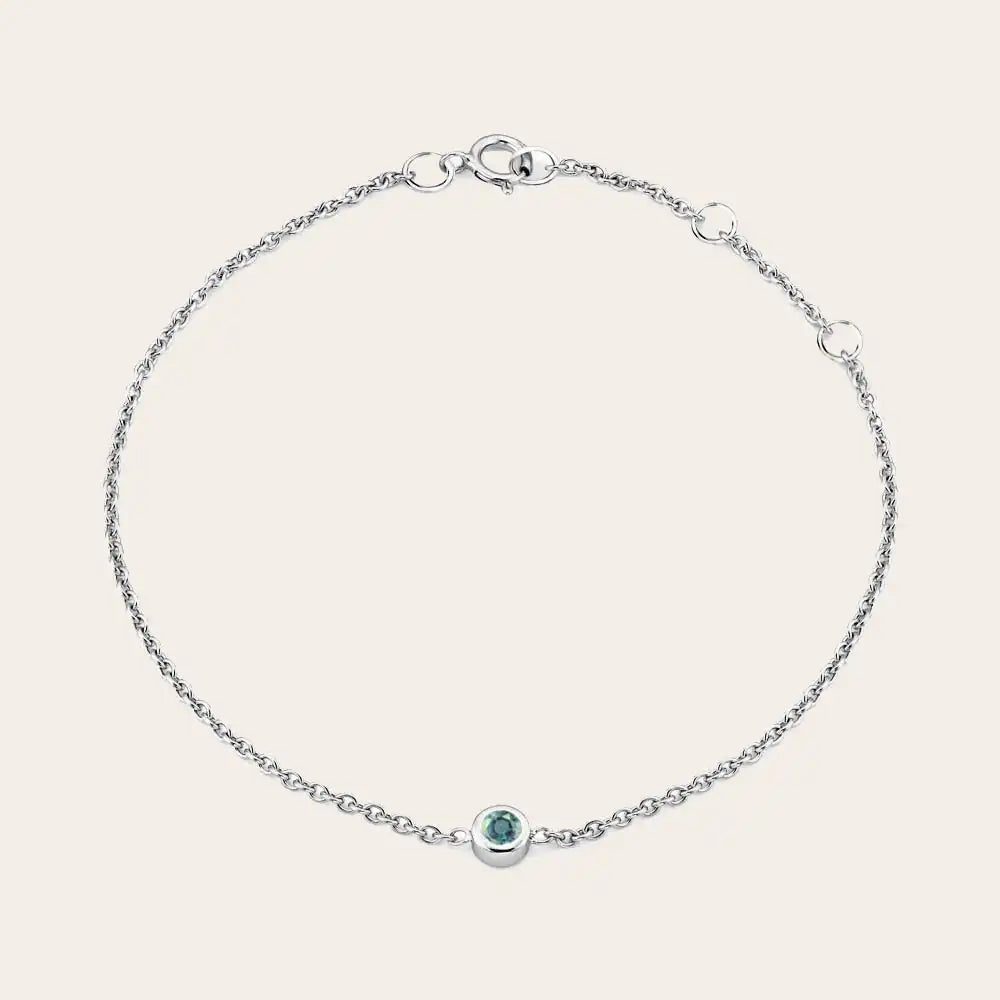 Bezel-set alexandrite bracelet flatlay showing vivid color change stone on curb chain silver variant--Sterling-silver variant--Alexandrite