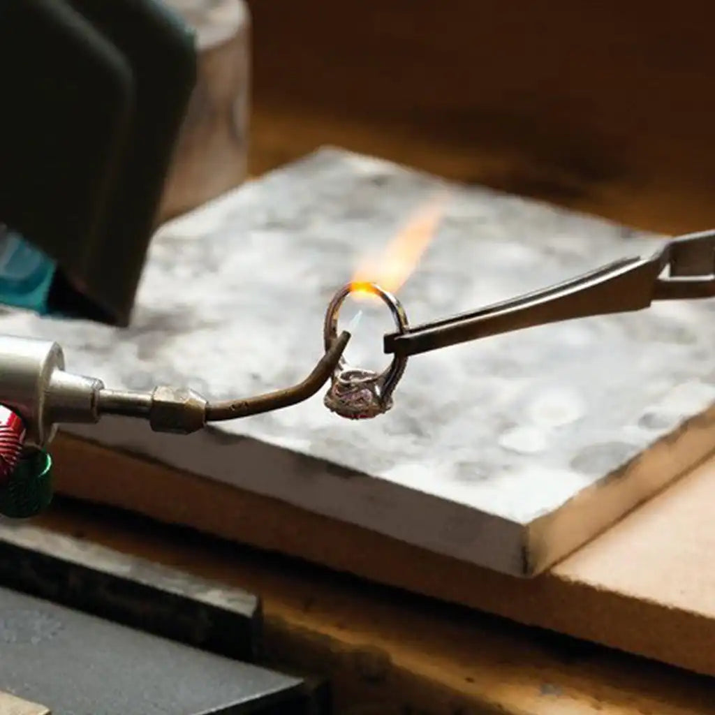 Image of custom engagement ring being soldered at jewlers bench