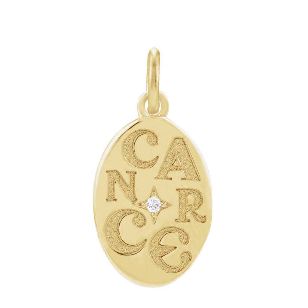 Close-up of engraved Cancer zodiac symbol on gold charm