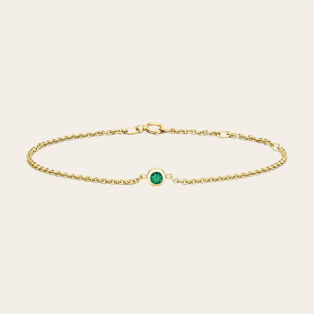 Bezel-set emerald bracelet flatlay showing vivid green stone on curb chain yellow gold variant--14K-yellow-gold variant--Emerald