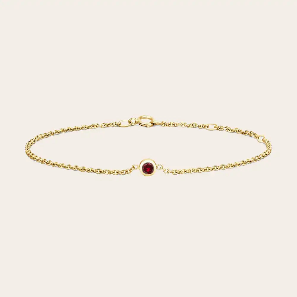Bezel-set garnet bracelet flatlay showing deep red stone and curb chain variant--14K yellow gold