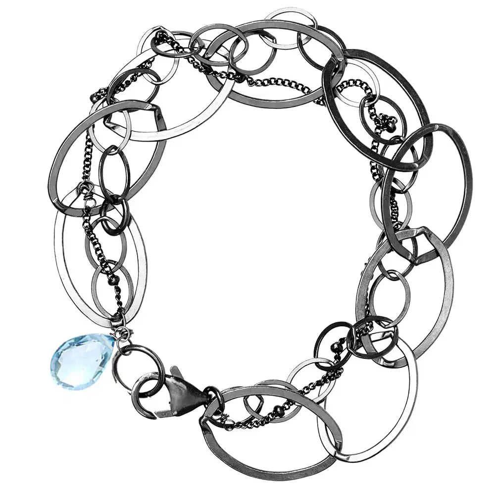 Natural swiss blue topaz woven chain bracelet in sterling silver, flat lay on neutral background