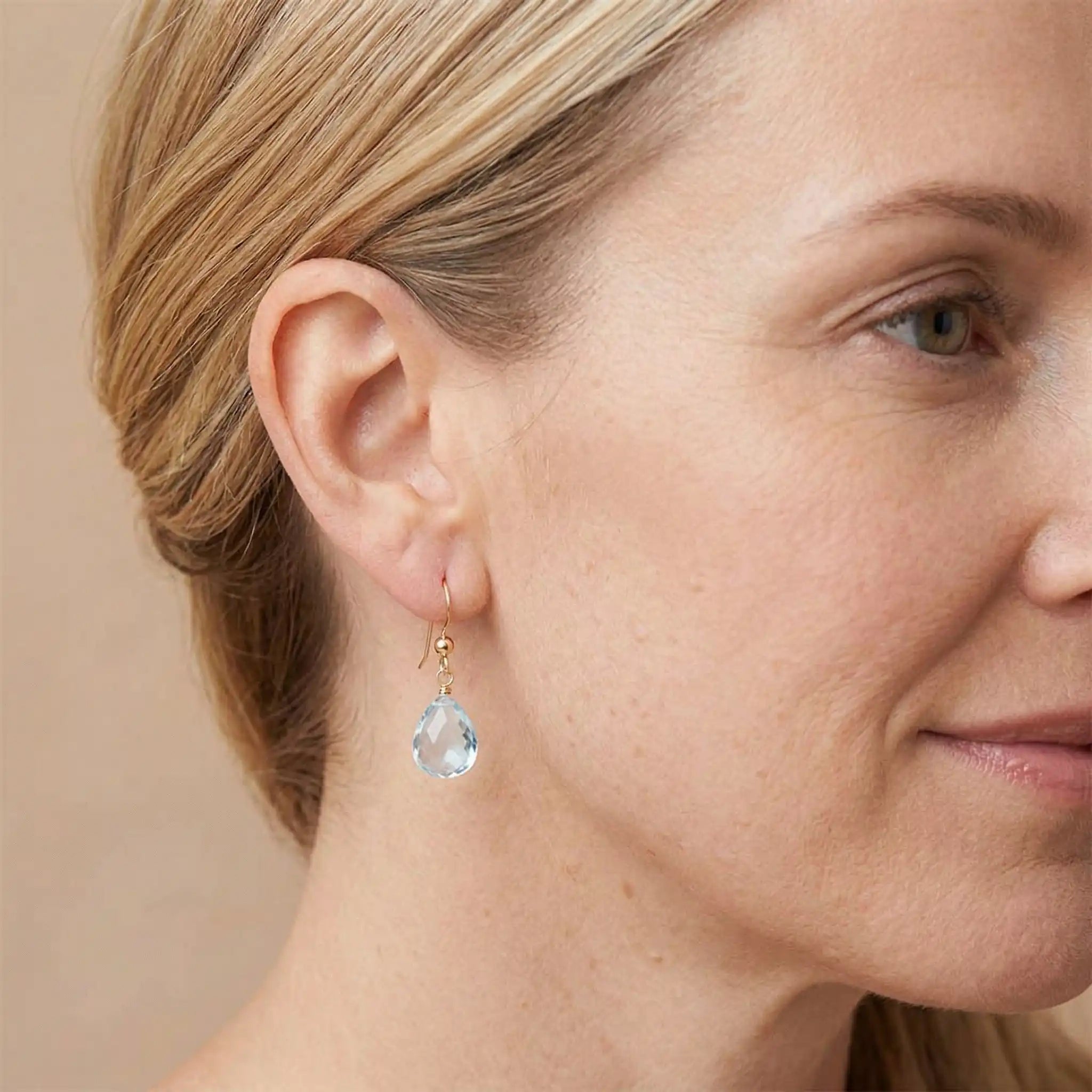 Custom gemstone drop earring in gold-fill, styled on model showing 1.5-inch drop length. variant--Gold-fill, variant--Sterling-silver, variant--14K-yellow-gold, variant--14K-white-gold variant--Swiss-Topaz