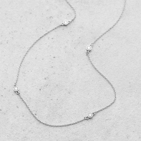 Diamond station necklace in 14k white gold featuring five floating round diamonds, delicate and timeless jewelry design.