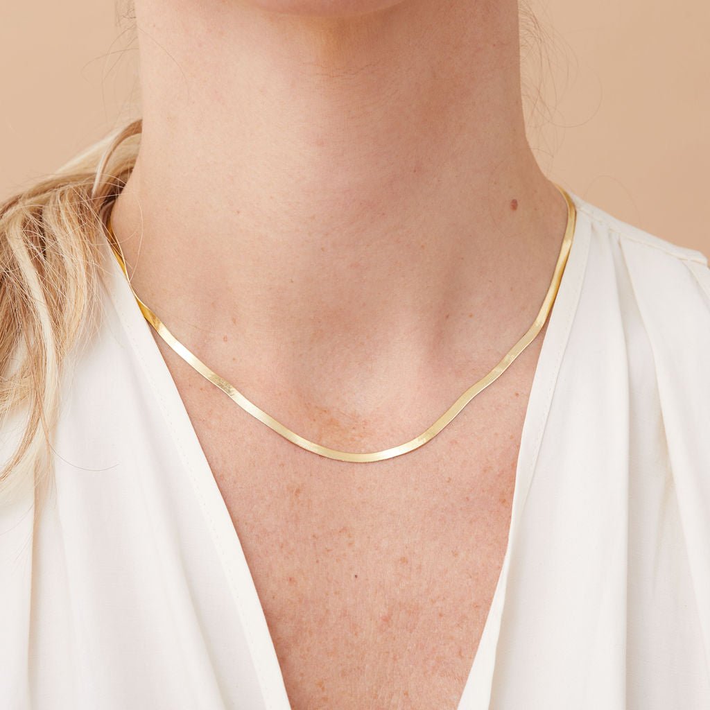 14k gold herringbone necklace styled as a statement piece with white blouse.