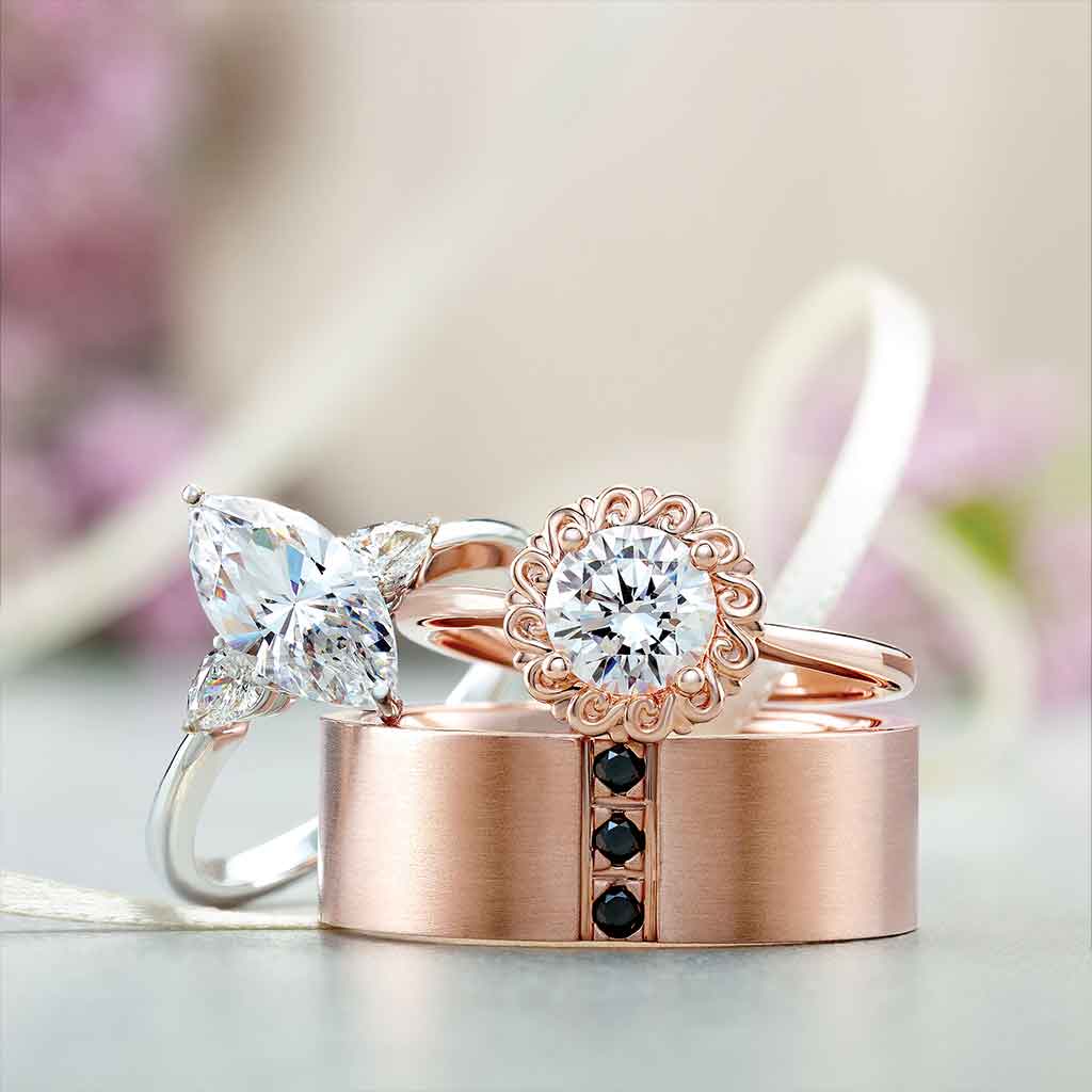 Three-stone engagement ring with pear side stones in 14K gold, diamond center, on hand