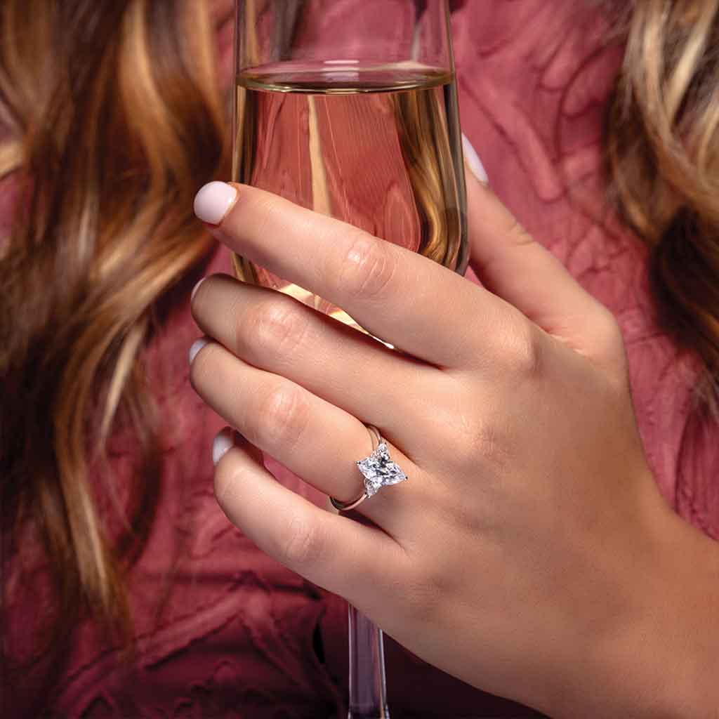 Three-stone engagement ring with pear side stones in 14K gold, diamond center, three-quarter angle