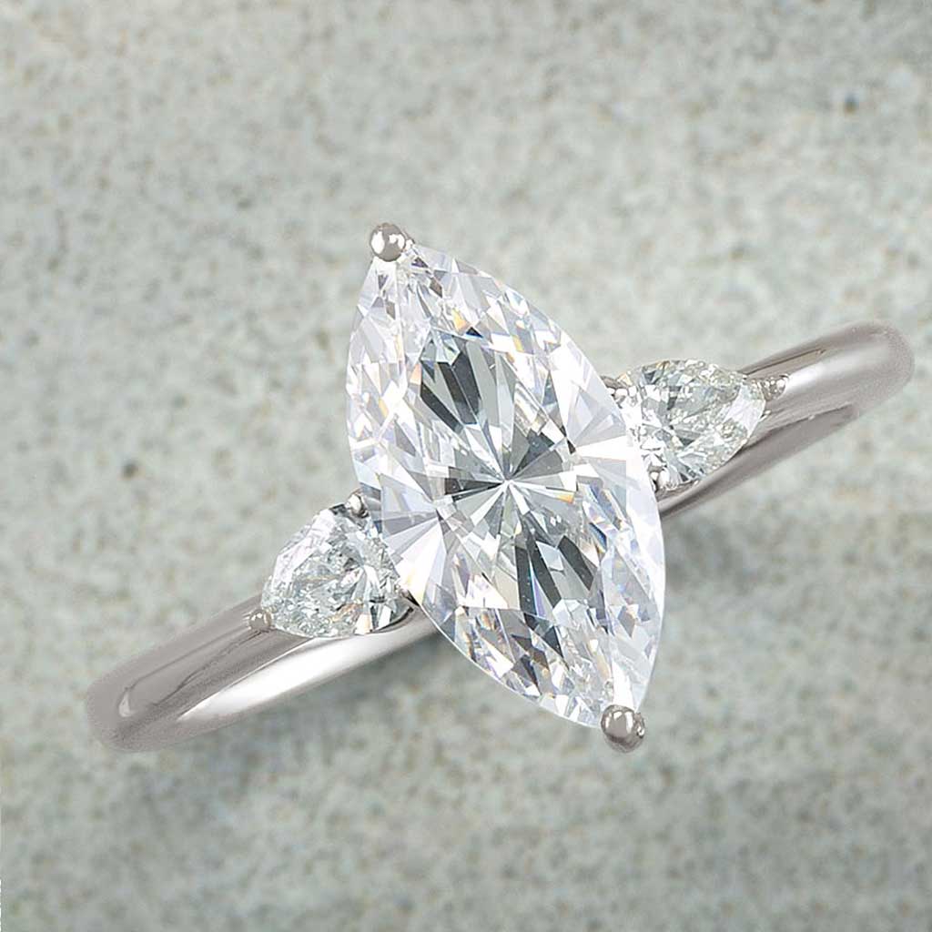 Three-stone engagement ring with pear side stones in 14K gold, diamond center, side profile