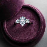 Three-stone engagement ring with round side stones in 14K gold, pear center, on hand