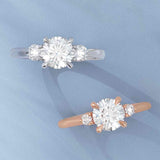 Three-stone engagement ring with round side stones in 14K gold, diamond center, showing setting detail