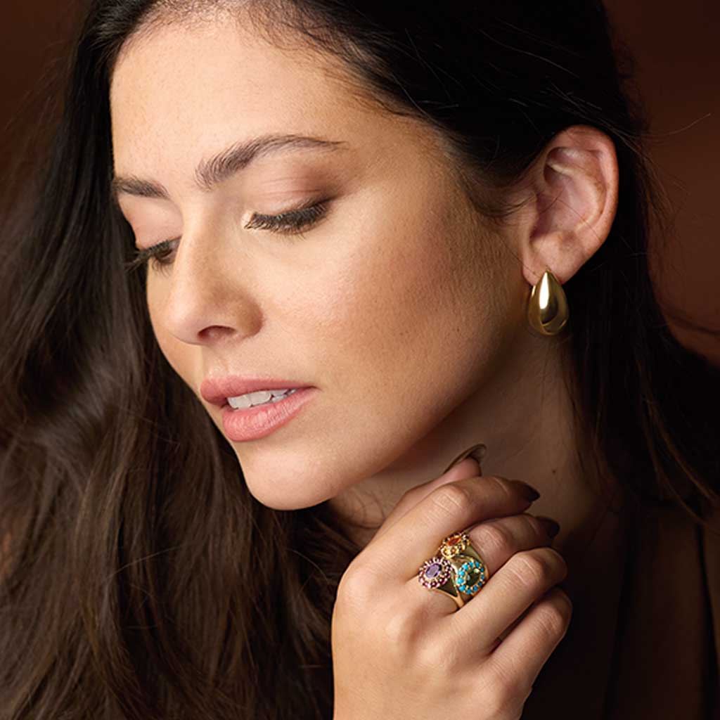 14K yellow gold tapered hoop earrings worn on ear for size reference