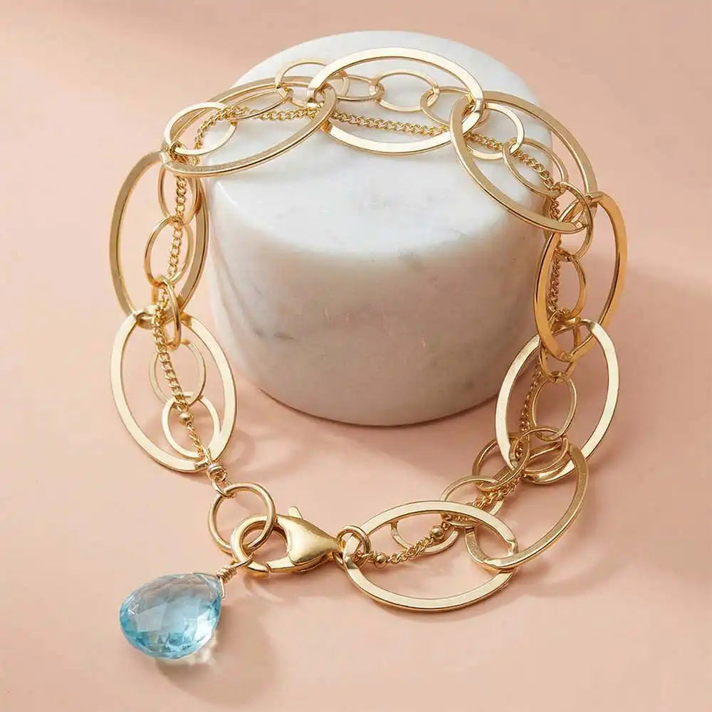 Gold chain bracelet with aquamarine accent.