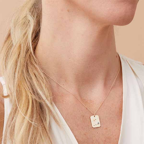 Constellation charm necklace with diamonds and birthstone on gold chain, styled on model