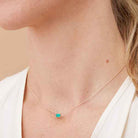 Minimalist birthstone necklace featuring a 5x3mm emerald shown on model