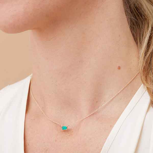 Minimalist birthstone necklace featuring a 5x3mm emerald shown on model