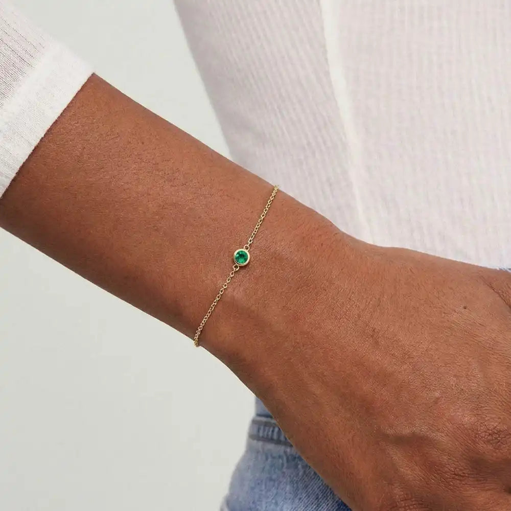 Model wearing bezel-set emerald bracelet. variant--14K-yellow-gold variant--Emerald