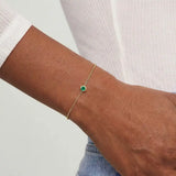 Model wearing bezel-set emerald bracelet. variant--14K-yellow-gold variant--Emerald
