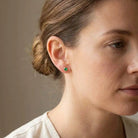Emerald birthstone stud earrings on model, vivid green studs at ear