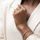 Gold link bracelet with diamond layered with a diamond tennis bracelet shown on wrist.