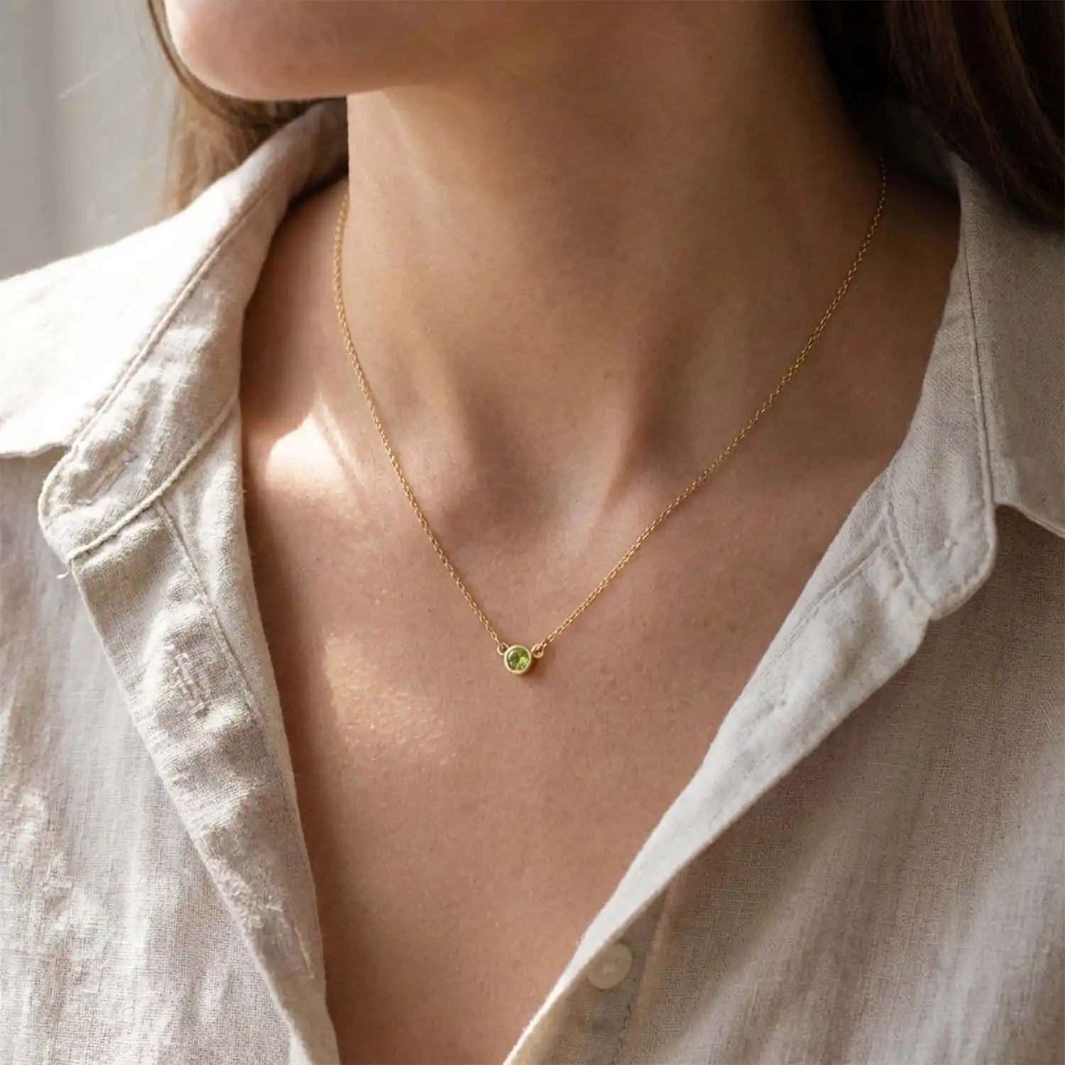 Bezel-set peridot necklace on model, layered at the collarbone