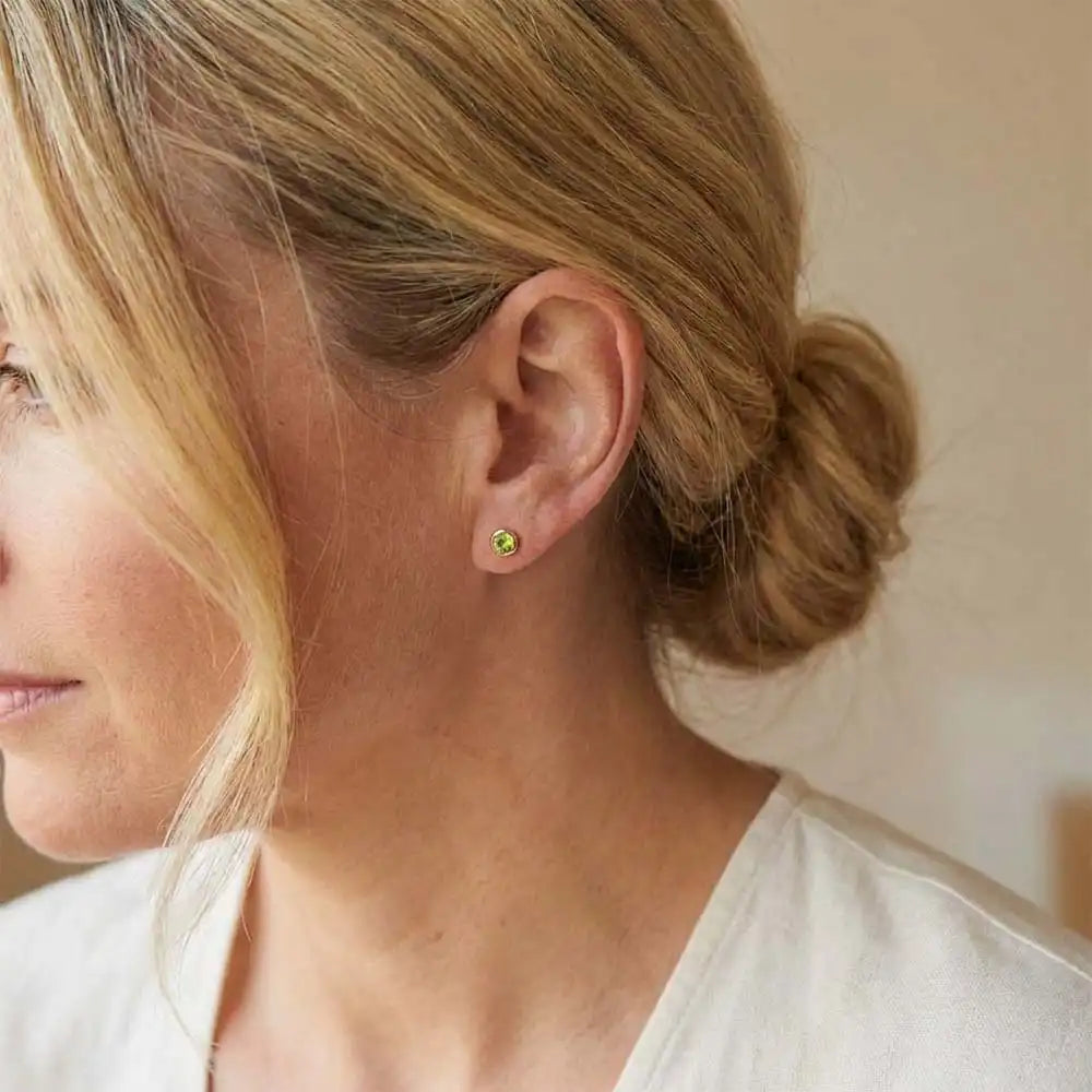 Peridot birthstone stud earrings on model, bright green studs at ear