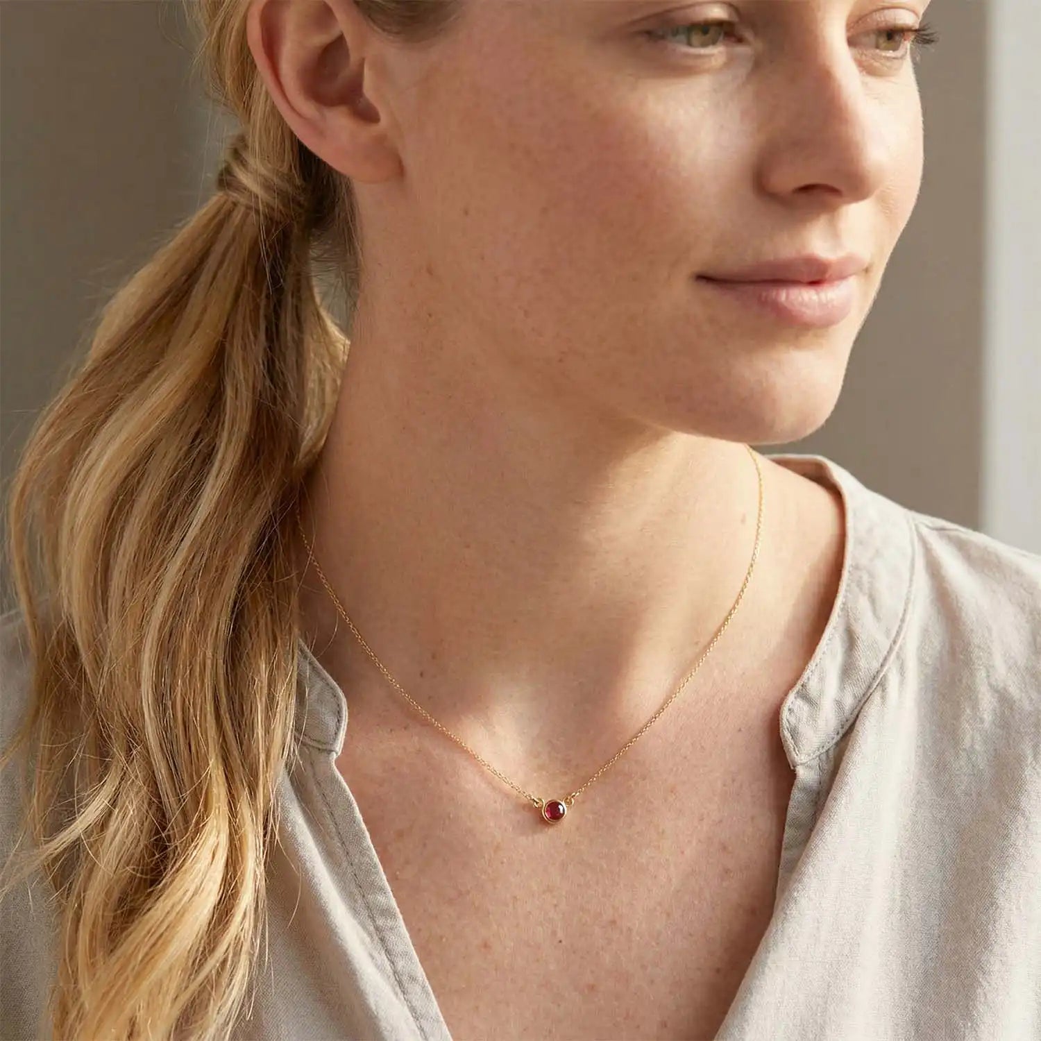 Bezel-set ruby necklace on model, layered at the collarbone