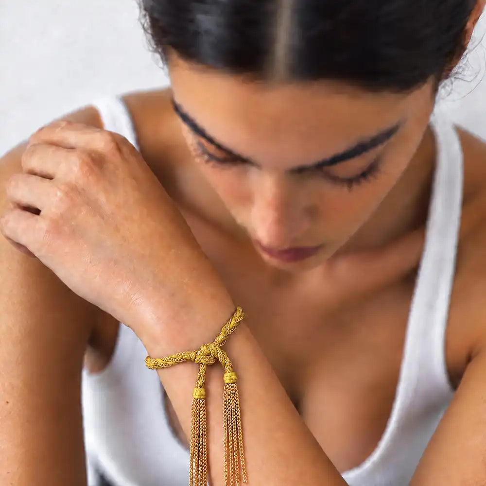 Yellow braided chain and silk tassel bracelet in 14K gold-fill worn on model