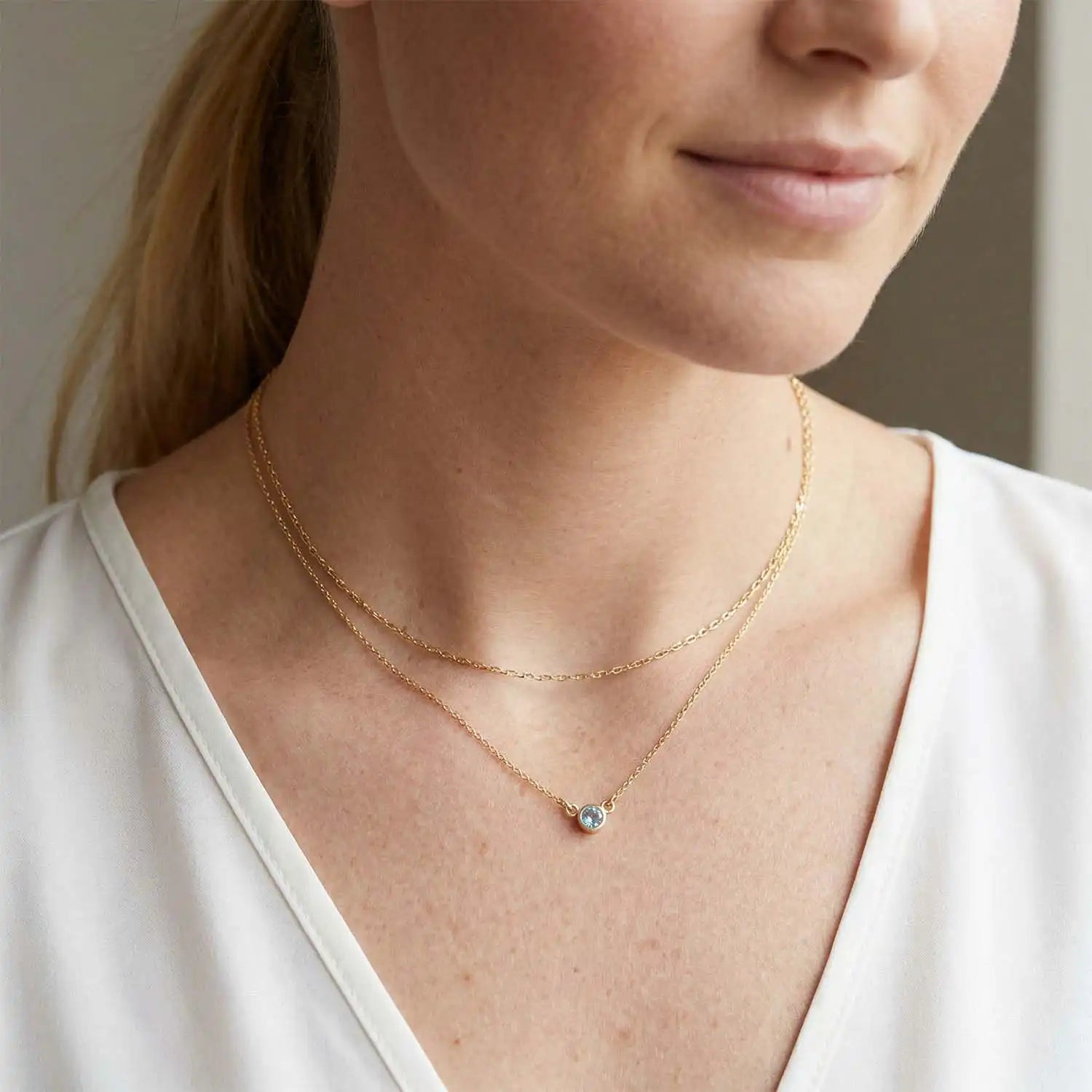 Bezel-set blue zircon necklace on model, layered at the collarbone