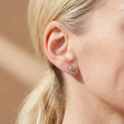 Zircon birthstone stud earrings on model, blue-teal studs at ear