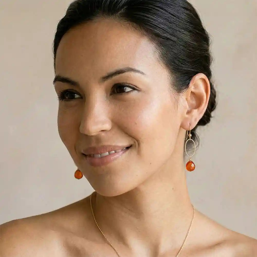 Woman wearing small faceted carnelian hoop earrings in yellow gold fill, warm orange gemstone with honey glow, lifestyle portrait. all-groups