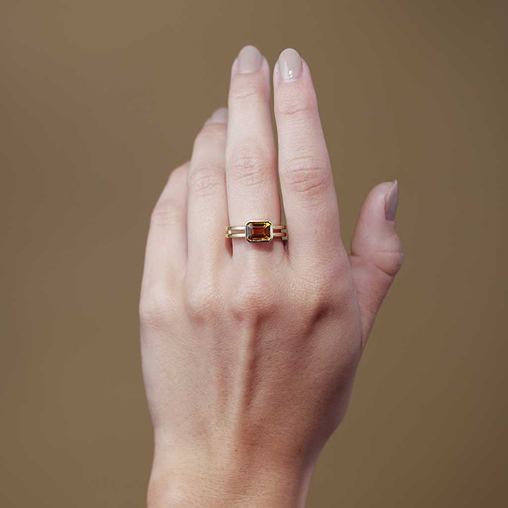 Citrine cocktail ring on model's hand, warm amber emerald-cut stone in yellow gold