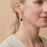 Close-up of natural black sapphire bezel dangle earring, showing dark stone and handcrafted wire detail