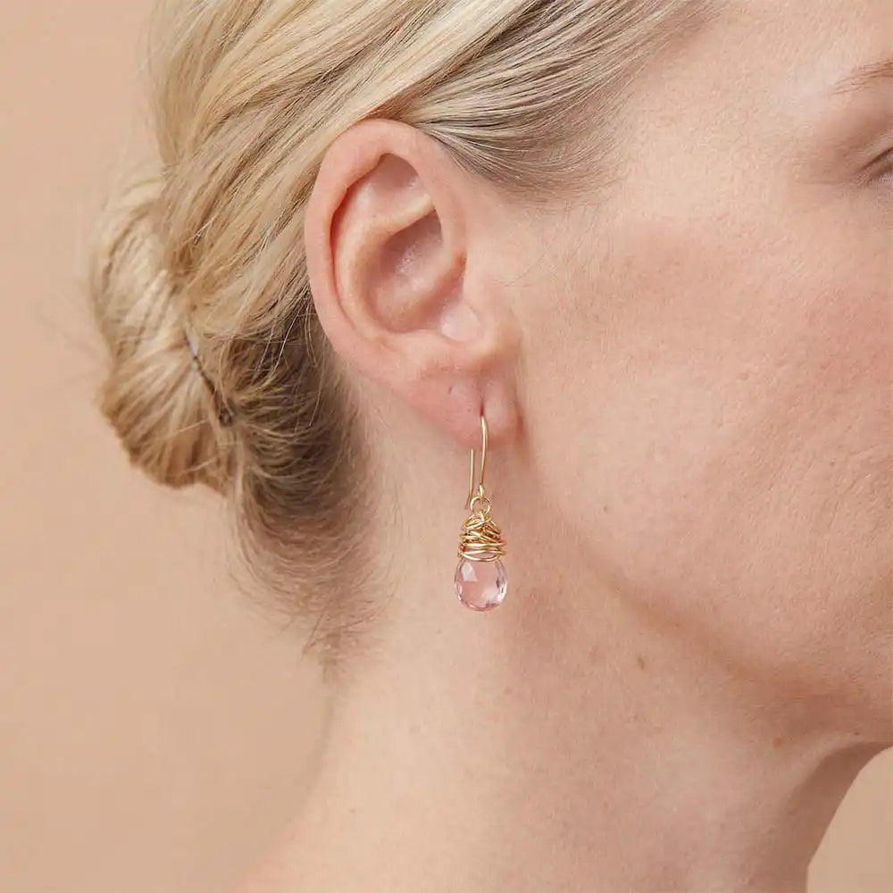 Close-up of natural pink topaz bezel dangle earring, showing rosy stone and handcrafted wire detail