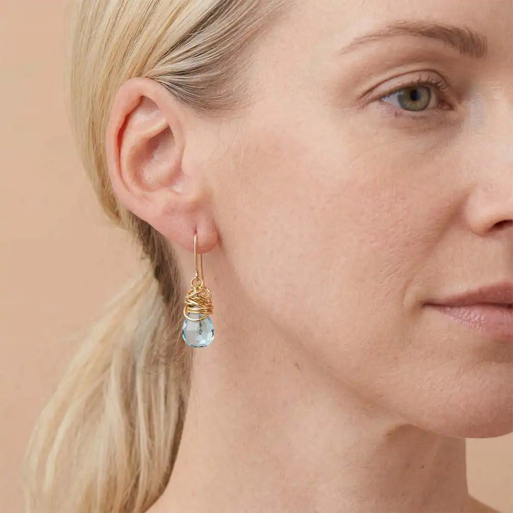 Close-up of natural swiss blue topaz bezel dangle earring, showing bright blue stone and handcrafted detail