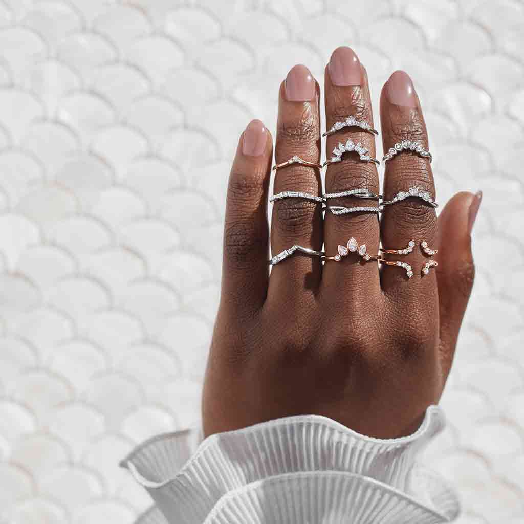 arabesque curved diamond band in 14k gold stacked with other bands on models hand