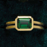 Emerald cocktail ring in yellow gold, close-up of emerald-cut stone in bezel setting