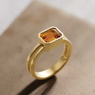 Bold emerald-cut citrine ring in 14K yellow gold, modern bezel style.
