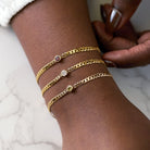14K gold gemstone link bracelets with bezel-set 5mm gem on curb chain layered on model.