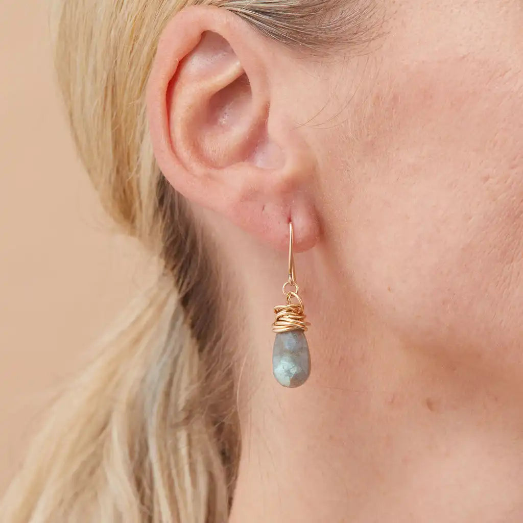Labradorite dangle earrings on model, showing color-shift from dark gray to iridescent blue in natural light
