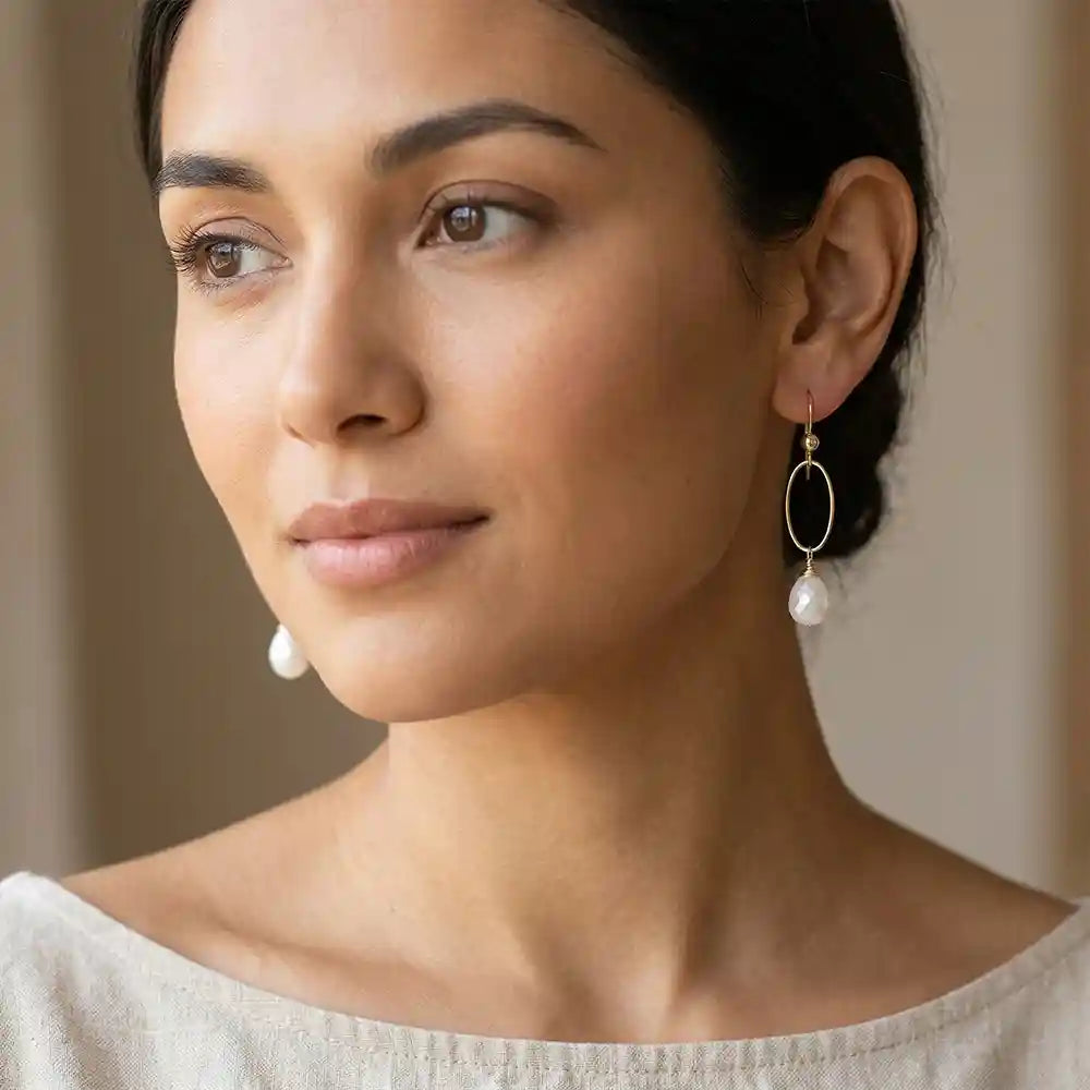 Woman wearing small pearl hoop earrings in yellow gold fill, lustrous white pearl with soft iridescent glow, lifestyle portrait. all-groups