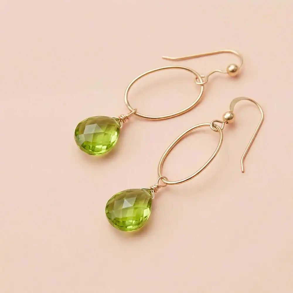 Faceted peridot drop earrings in yellow gold fill, bright lime-green gemstone teardrop briolette suspended from slim oval gold link, blush background. all-groups