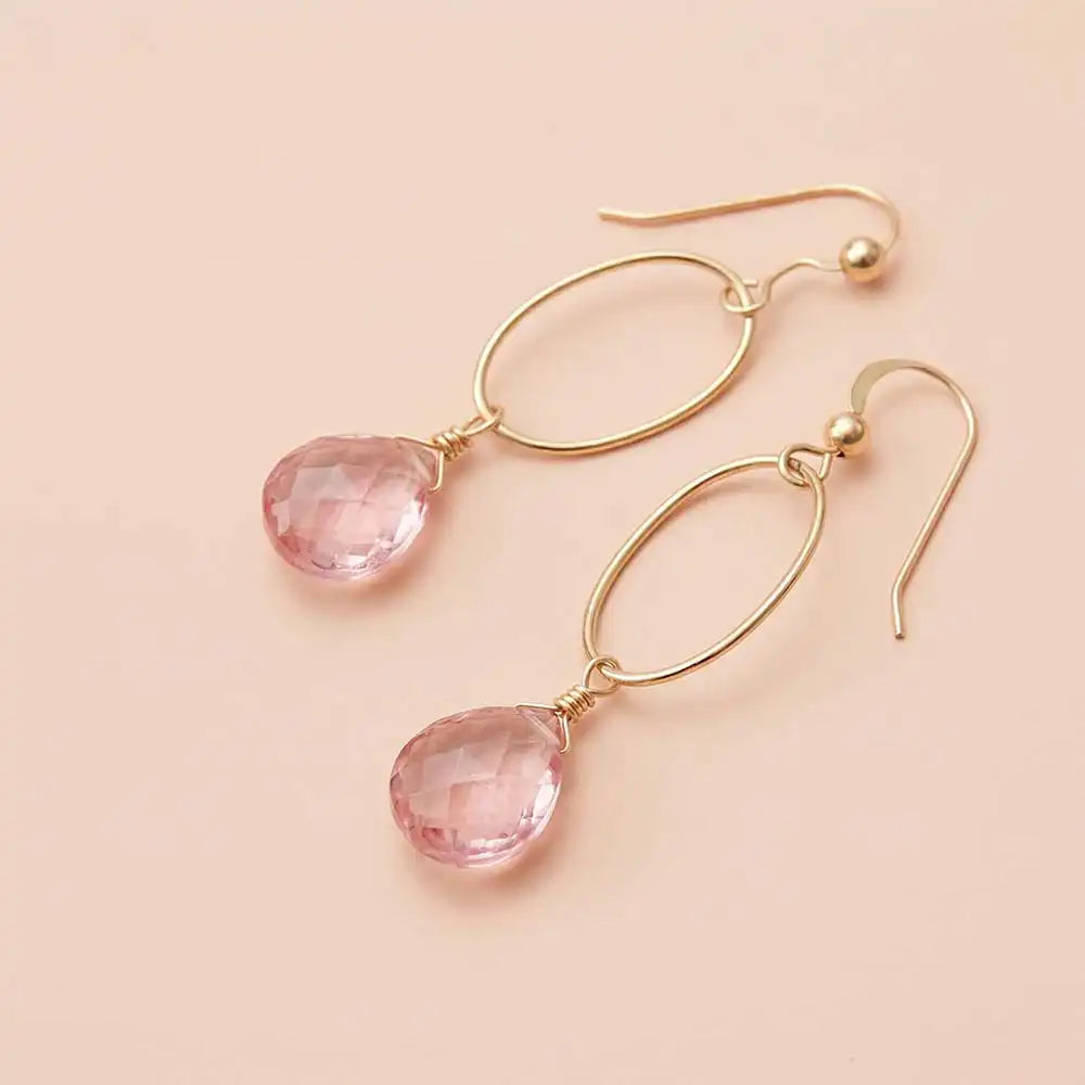 Faceted pink topaz drop earrings in yellow gold fill, soft blush-pink
gemstone teardrop briolette suspended from slim oval gold link,
blush background. all-groups