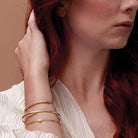 Stacked gold bracelets show on wrist