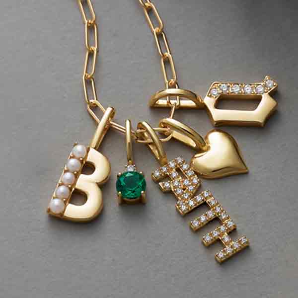 Diamond faith charm in 14K gold with subtle diamond accents layered with other charms