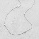 Diamond station necklace in 14k white gold featuring five floating round diamonds, delicate and timeless jewelry design.