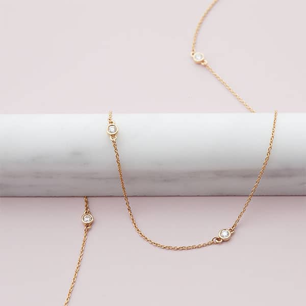 Diamond station necklace in 14k yellow gold with five floating diamonds, elegant everyday jewelry handcrafted for layering.